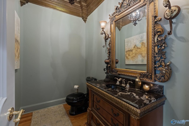 bathroom featuring toilet, wood-type flooring, vanity, and ornamental molding