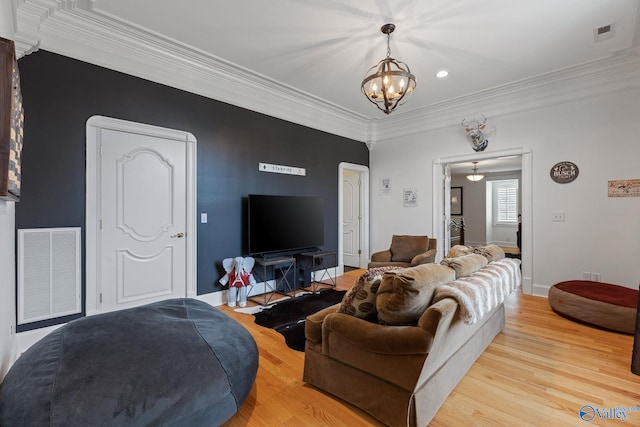 living room with a notable chandelier, ornamental molding, and light hardwood / wood-style floors