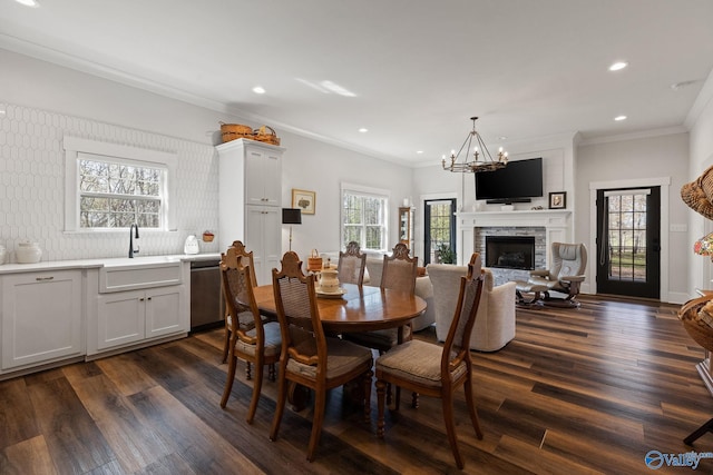 dining space with a fireplace, ornamental molding, sink, and dark hardwood / wood-style flooring