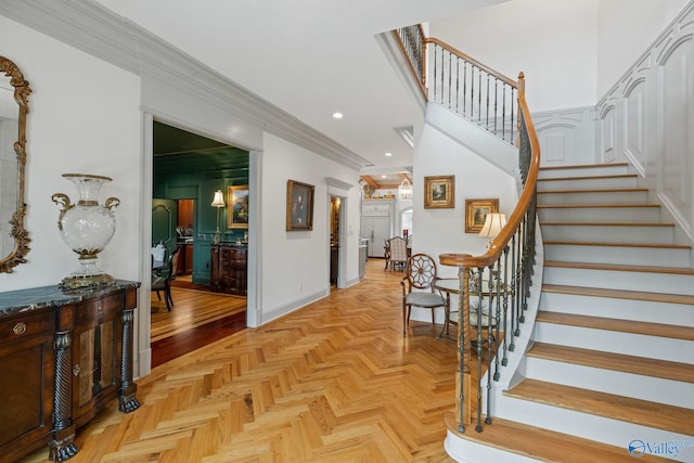 foyer with crown molding and light parquet floors