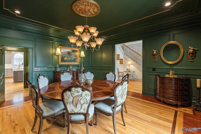 dining area with a notable chandelier, light hardwood / wood-style flooring, sink, and crown molding