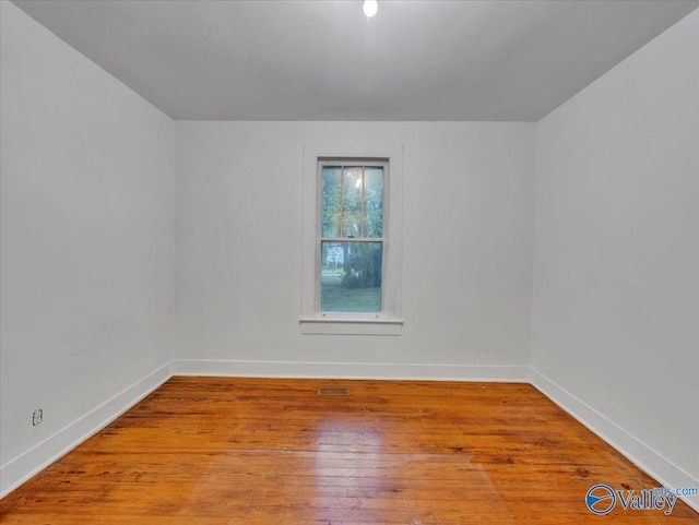 unfurnished room featuring visible vents, hardwood / wood-style flooring, and baseboards