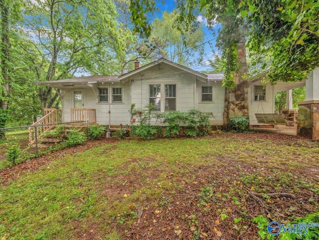 view of front of home with a chimney, fence, and a front yard