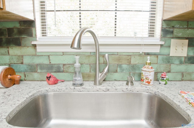 interior details with sink, backsplash, and light stone countertops