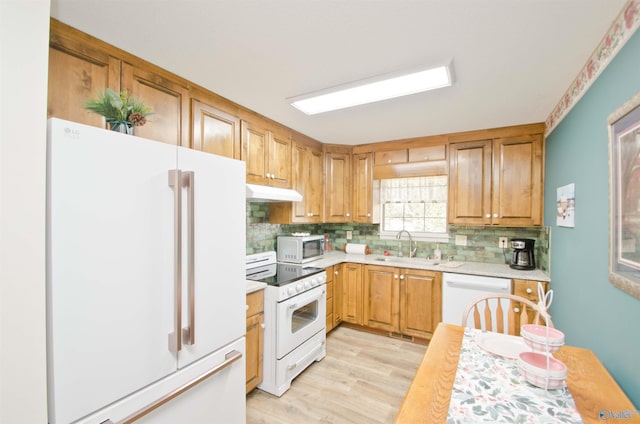 kitchen with white appliances, light hardwood / wood-style floors, sink, and decorative backsplash