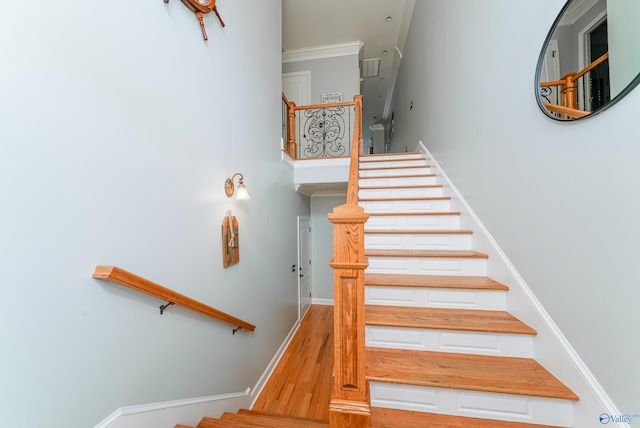 staircase featuring hardwood / wood-style floors and ornamental molding