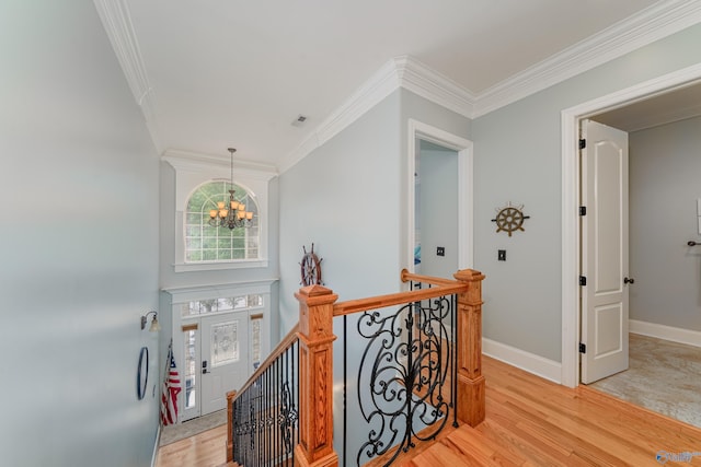 corridor with ornamental molding, light hardwood / wood-style flooring, and a notable chandelier