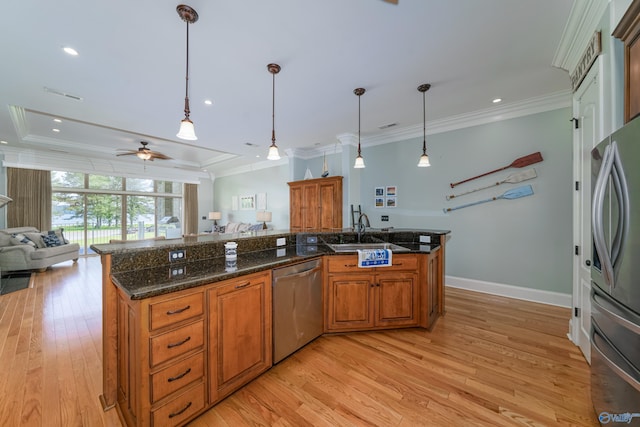 kitchen with sink, crown molding, hanging light fixtures, dark stone countertops, and appliances with stainless steel finishes