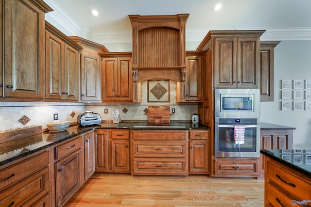 kitchen with tasteful backsplash, crown molding, appliances with stainless steel finishes, and dark stone counters