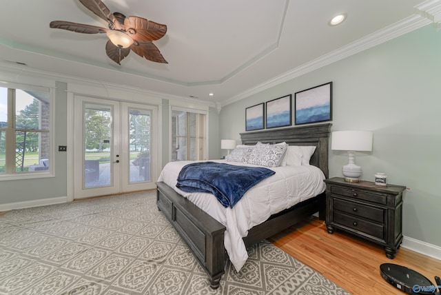 bedroom with light hardwood / wood-style flooring, ceiling fan, access to exterior, a tray ceiling, and french doors