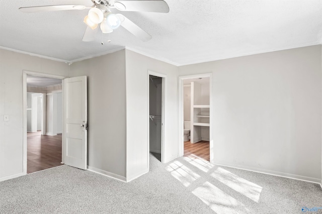 unfurnished bedroom with a spacious closet, ceiling fan, a closet, and light carpet