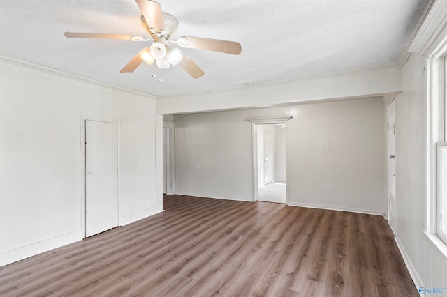 empty room with ceiling fan, crown molding, a textured ceiling, and dark hardwood / wood-style floors