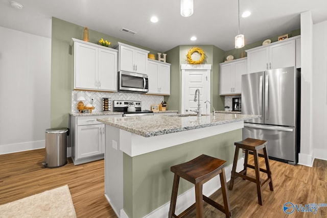 9130 Monteagle Blvd, Owens Cross Roads, AL 35763 - kitchen featuring appliances with stainless steel finishes, baseboards, light wood-style flooring, decorative backsplash, and a breakfast bar area
