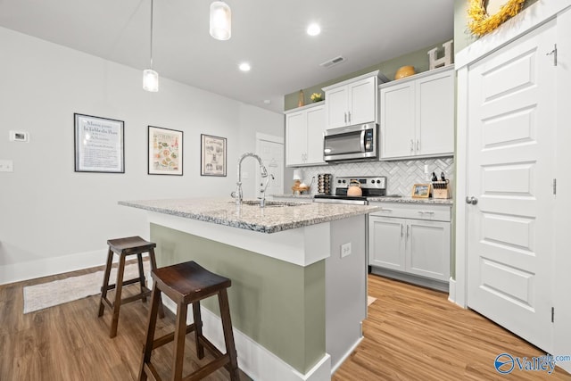 9130 Monteagle Blvd, Owens Cross Roads, AL 35763 - kitchen featuring appliances with stainless steel finishes, light wood-style flooring, a kitchen island with sink, decorative backsplash, and recessed lighting