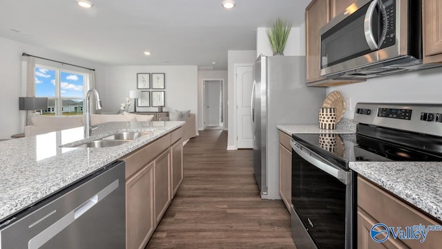 kitchen with light stone counters, a sink, appliances with stainless steel finishes, and dark wood-style flooring