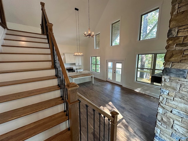 stairway with hardwood / wood-style flooring, high vaulted ceiling, french doors, and a notable chandelier