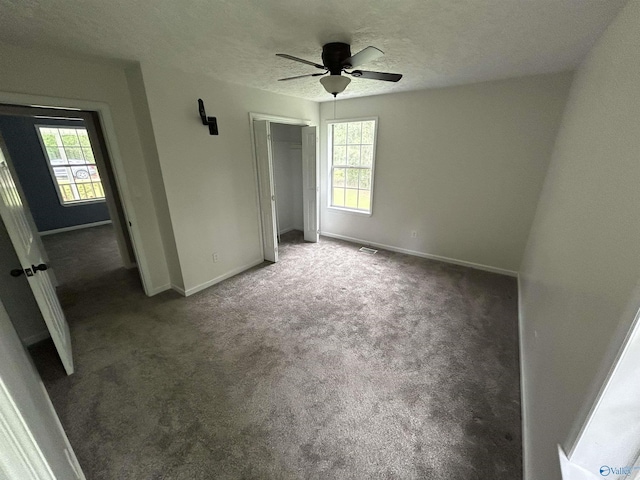3185 Reeves Rd, Hokes Bluff, AL 35903 - unfurnished bedroom with multiple windows, baseboards, a closet, carpet flooring, and a textured ceiling