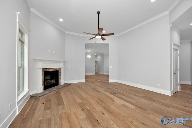 unfurnished living room with crown molding, ceiling fan, a fireplace, and light hardwood / wood-style flooring