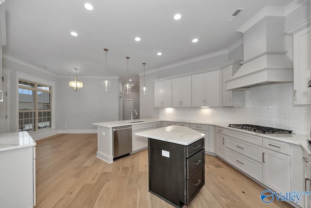 kitchen with custom exhaust hood, hanging light fixtures, kitchen peninsula, a kitchen island, and stainless steel appliances