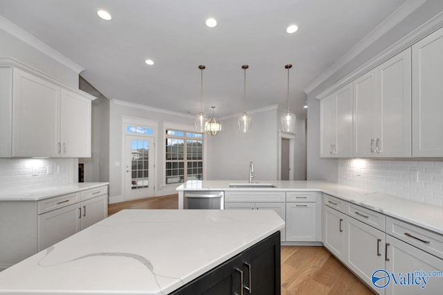 kitchen with pendant lighting, sink, light stone counters, a kitchen island, and stainless steel dishwasher