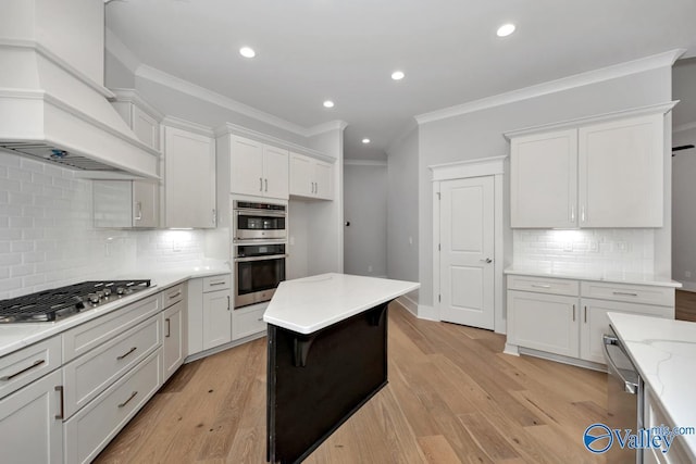 kitchen featuring tasteful backsplash, white cabinetry, custom range hood, and appliances with stainless steel finishes