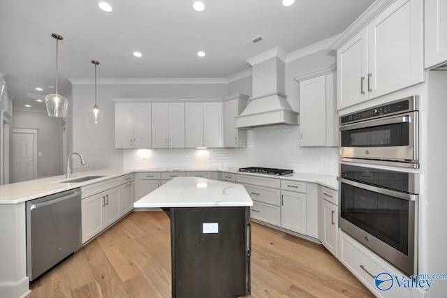 kitchen featuring decorative light fixtures, white cabinetry, sink, custom exhaust hood, and stainless steel appliances