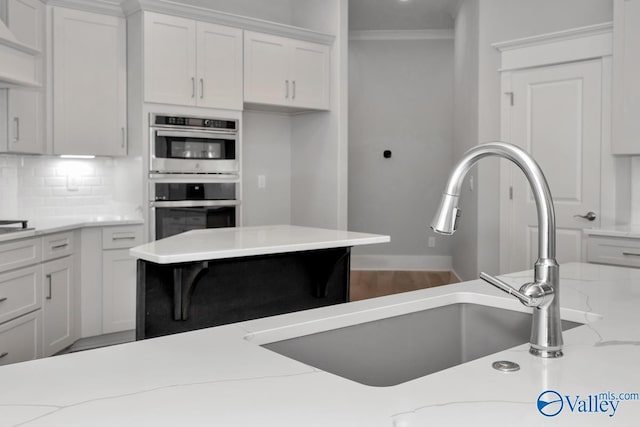 kitchen with light stone countertops, sink, and white cabinets