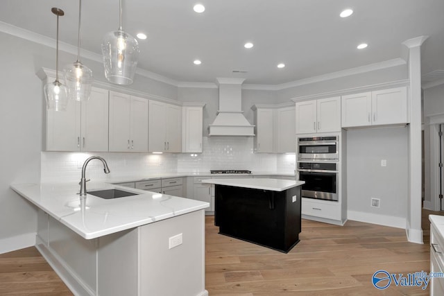 kitchen featuring white cabinetry, a kitchen island, sink, and hanging light fixtures