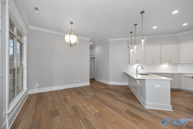 kitchen featuring white cabinetry, sink, pendant lighting, and kitchen peninsula