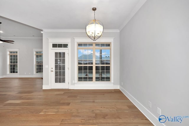 unfurnished dining area featuring hardwood / wood-style floors, crown molding, and ceiling fan with notable chandelier