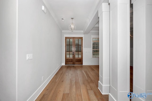 corridor featuring crown molding, light hardwood / wood-style flooring, and french doors