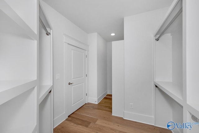 walk in closet with light hardwood / wood-style floors