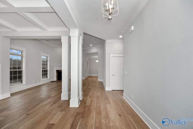 interior space with coffered ceiling, a notable chandelier, ornamental molding, light hardwood / wood-style floors, and beamed ceiling