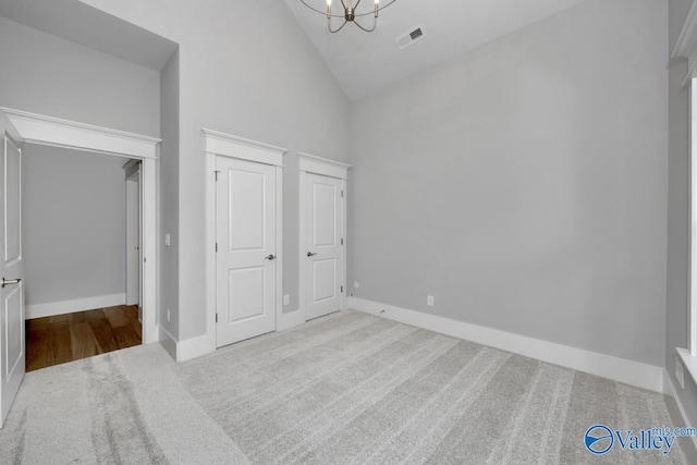 unfurnished bedroom with light carpet, a notable chandelier, and high vaulted ceiling