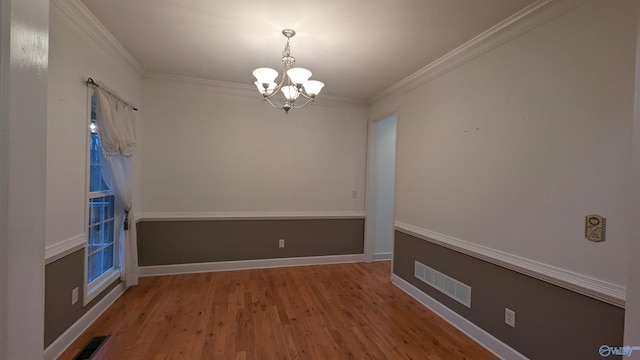 spare room with ornamental molding, hardwood / wood-style flooring, and a notable chandelier