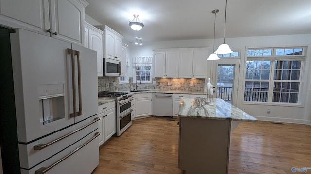 kitchen with white cabinets, light hardwood / wood-style floors, light stone countertops, and high quality appliances