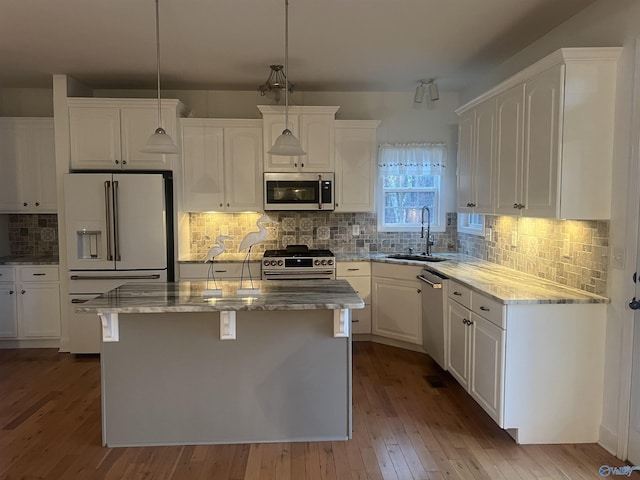 kitchen with stainless steel appliances, decorative backsplash, sink, a kitchen island, and light hardwood / wood-style flooring