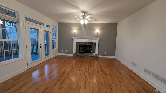 unfurnished living room with a fireplace, french doors, ceiling fan, and hardwood / wood-style floors