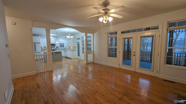 interior space featuring ceiling fan with notable chandelier, light hardwood / wood-style floors, and french doors