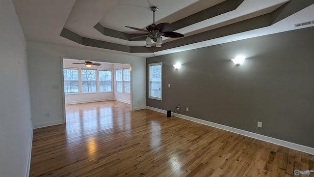 unfurnished room with ceiling fan, wood-type flooring, and a tray ceiling