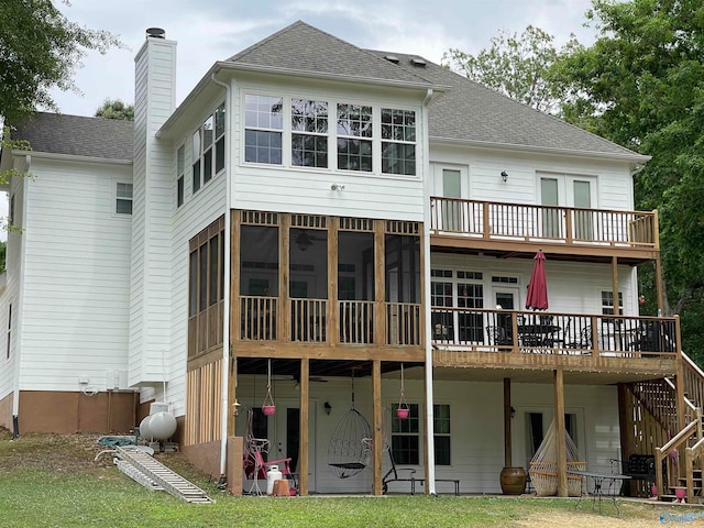 back of property featuring a sunroom, a deck, and a lawn