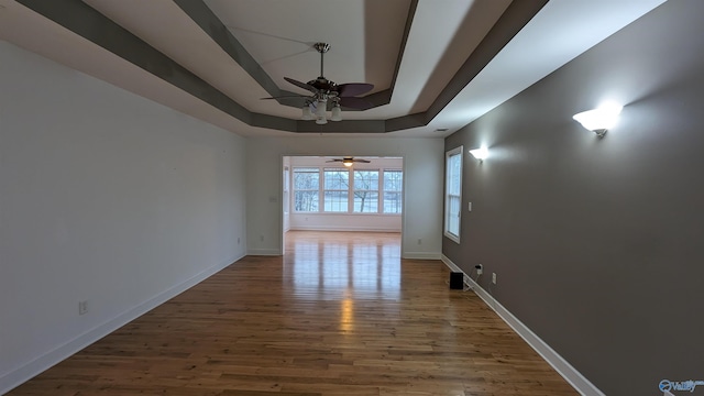 spare room featuring hardwood / wood-style flooring, ceiling fan, and a raised ceiling