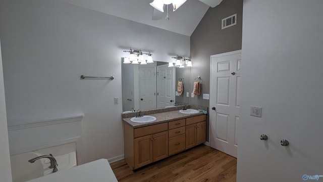 bathroom featuring lofted ceiling, a bathing tub, ceiling fan, dual vanity, and hardwood / wood-style floors