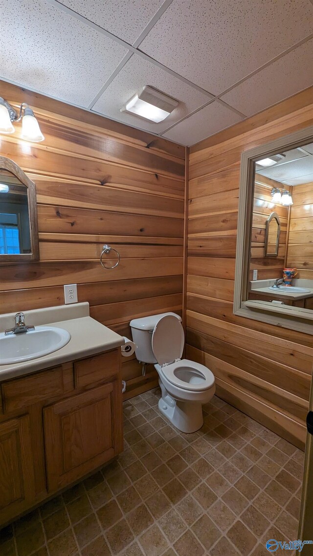 bathroom featuring tile patterned flooring, a drop ceiling, toilet, and vanity