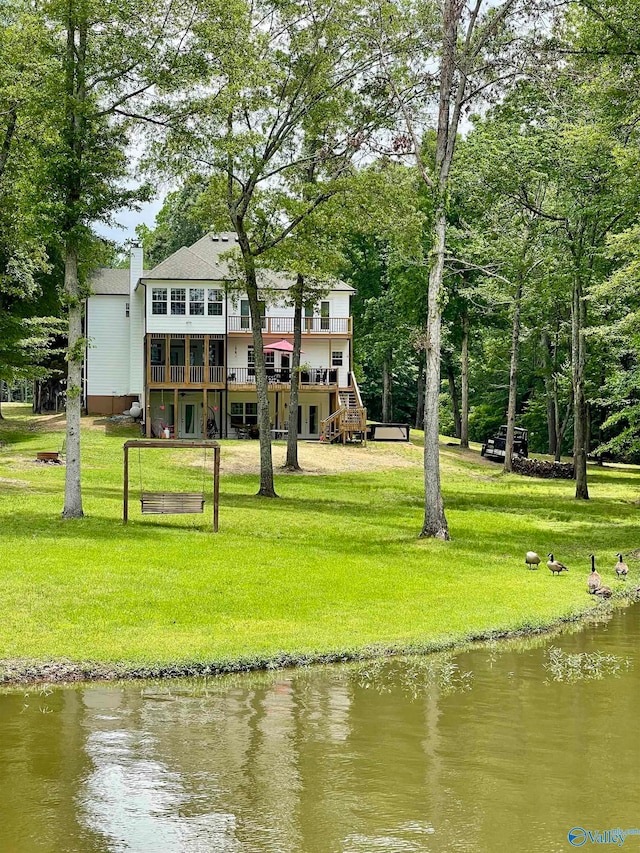 rear view of property with a water view and a lawn