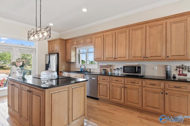 kitchen with appliances with stainless steel finishes, a kitchen island, an inviting chandelier, and light hardwood / wood-style flooring