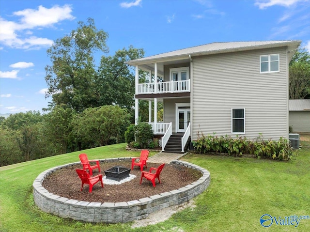 back of house featuring a lawn, a balcony, and a fire pit