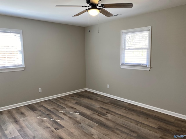 unfurnished room featuring dark wood-style floors, baseboards, visible vents, and a ceiling fan