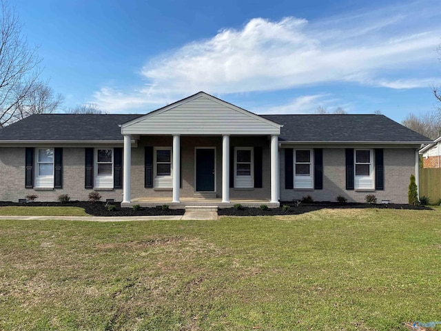 greek revival house with a front yard, covered porch, crawl space, brick siding, and roof with shingles