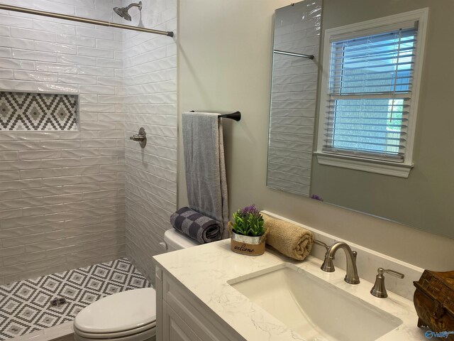 bathroom featuring toilet, vanity, and a tile shower